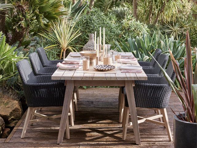 wooden dining set in lush garden with plant wall