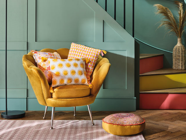 colourful hallway ideas: mustard accent chair with sage green-painted stairs and accent runners