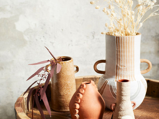 Dried flowers arranged in neutral vases on a side table