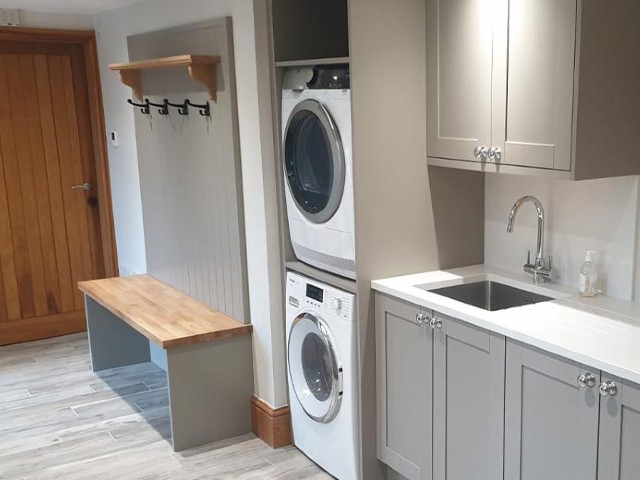 grey utility room with sink, washing machine and dryer, and storage for coats and shoes