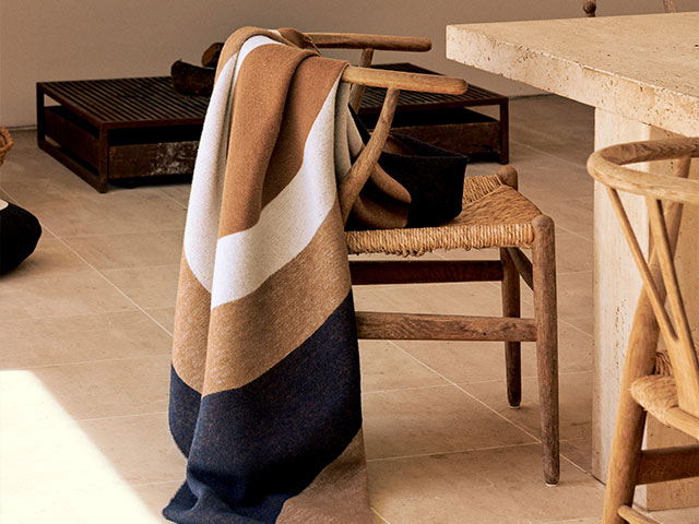 designer blanket by Marimekko with geometric pattern draped over the back of a woven chair