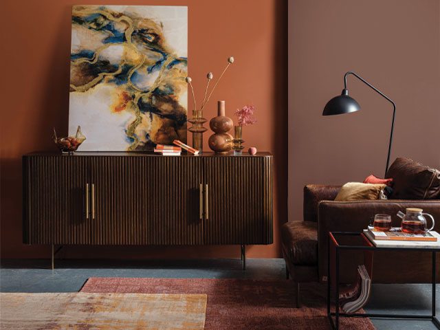 70s style interiors with brown walls, fluted wooden cabinet and orange accessories
