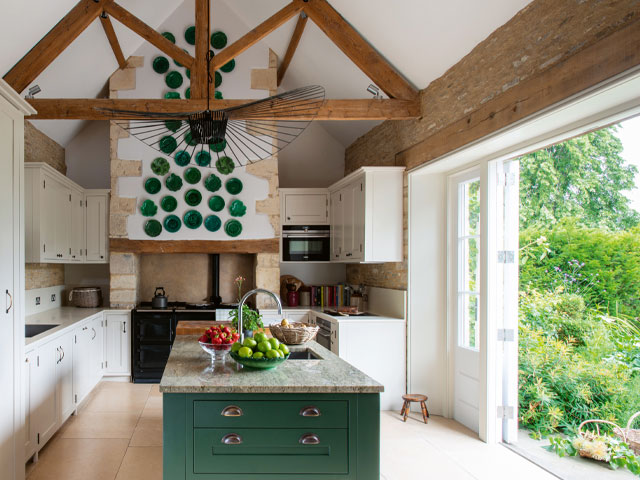 A country kitchen in the Cotswolds with vaulted oak-beamed ceiling and feature fireplace with arga