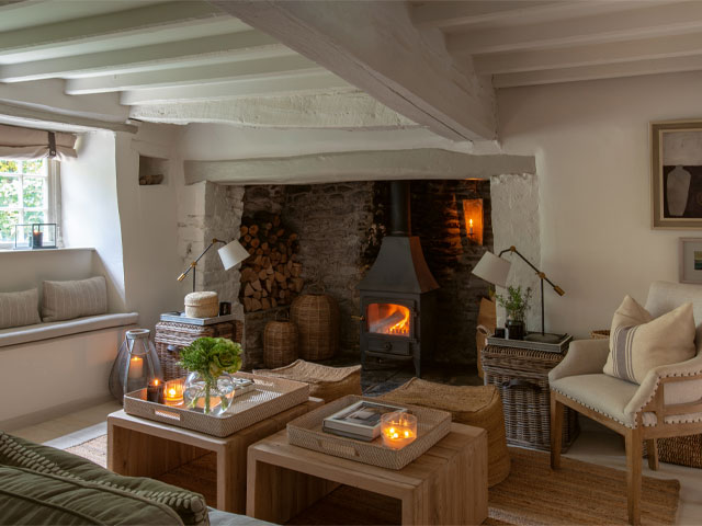 A cosy Cotswold cottage living room with original brick fireplace and modern wood burning stove