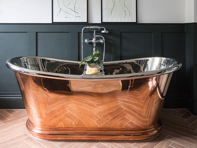 copper freestanding bathtub in period house with green panelled walls 