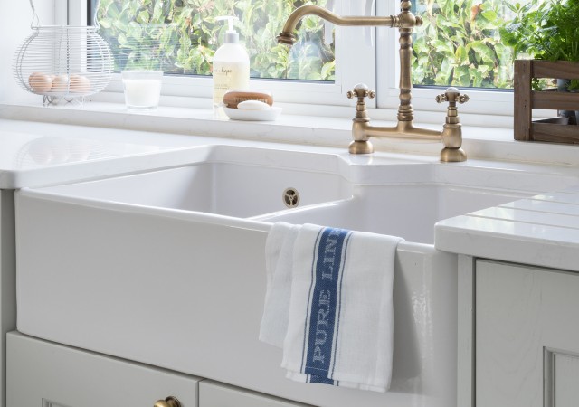 double butler sink with curved brass tap in a traditional kitchen