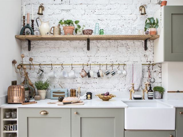 country-style sink area with painted, exposed bricks, scaffold plank shelf and brass mug rail