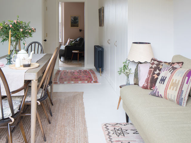 Kitchen-diner extension with white-washed floors leading to a pink living room 