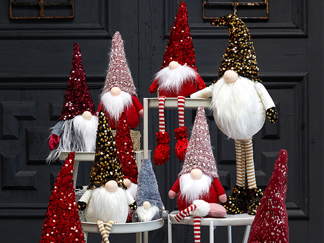 standing and sitting sparkly christmas gonks arranged on a plant stand in front of a grey wall