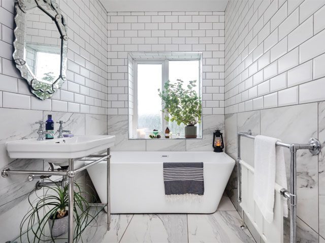 bathroom with mixed marble and white metro tiles, freestanding bath and ornate silver mirror above the sink
