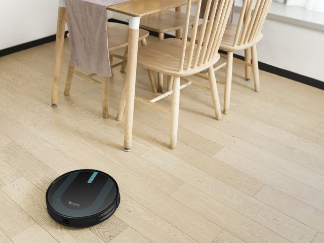 Proscenic 850T robot vacuum cleaner on a laminate floor with dining table in the background