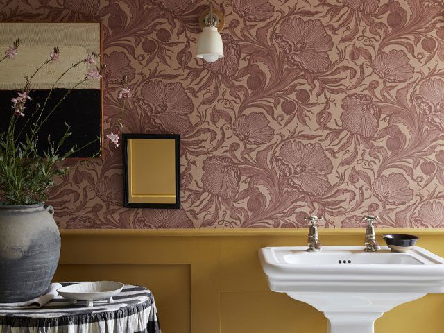 bathroom with half panelled walls painted mustard yellow and top half of the wall papered in pink floral wallpaper 