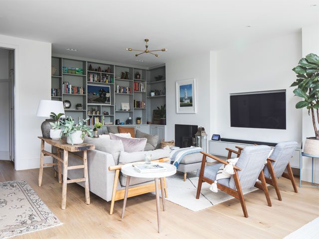 the living area in an open plan kitchen, dining and living space with built in wall-to-wall shelving