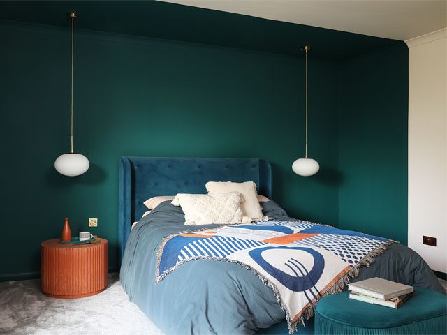 bedroom with forest green feature wall and pendant lights with long brass fixtures