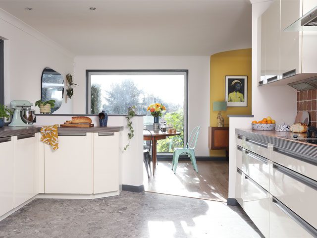 transforming a Scottish bungalow: white kitchen with gloss cabinets and terrazzo-effect LVT flooring leading on to dining room and garden