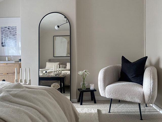 ivory accent chair in a bedroom painted in warm whites and creams