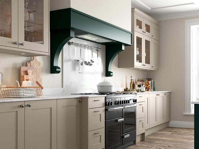 beige kitchen cabinets in a large kitchen with range oven and forest green painted cooker hood surround