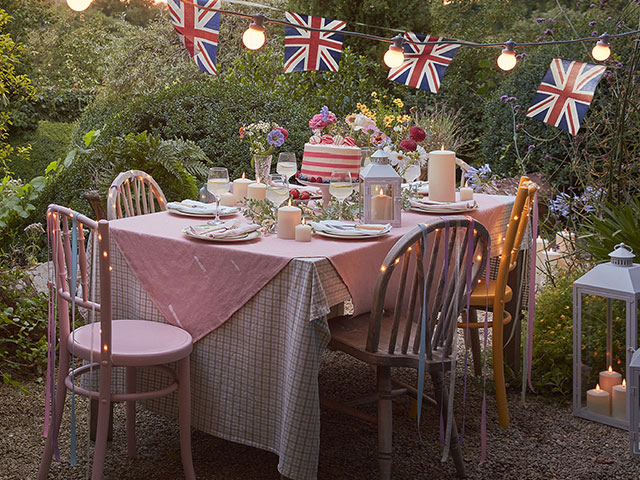 royalcore decor: a king's coronation garden party table set up with bunting, cake and lanterns