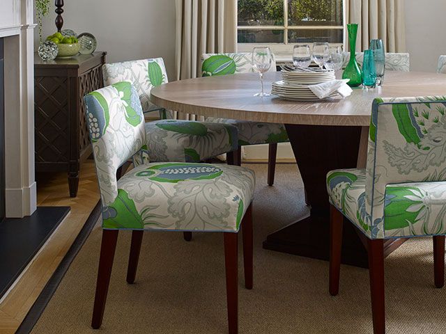 Upholstered green and white patterned dining chairs in wooden neutral toned dining room