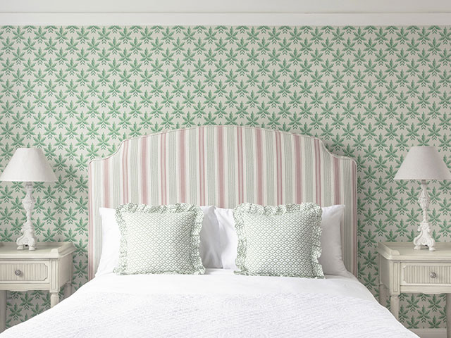 upholstered headboard with patterned wallpaper behind