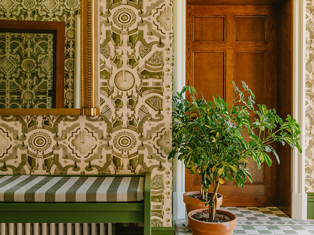 Patterned wallpaper hallway with side bench and foliage 