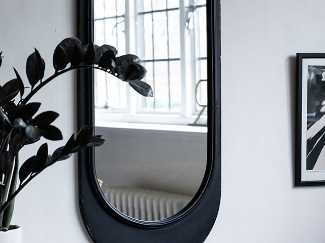 Black oval mirror in white hallway space