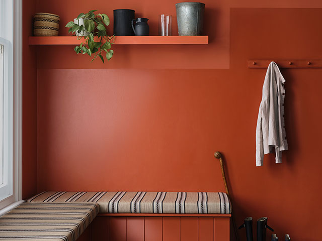 Bench seating in hallway with red wall and shelving unit