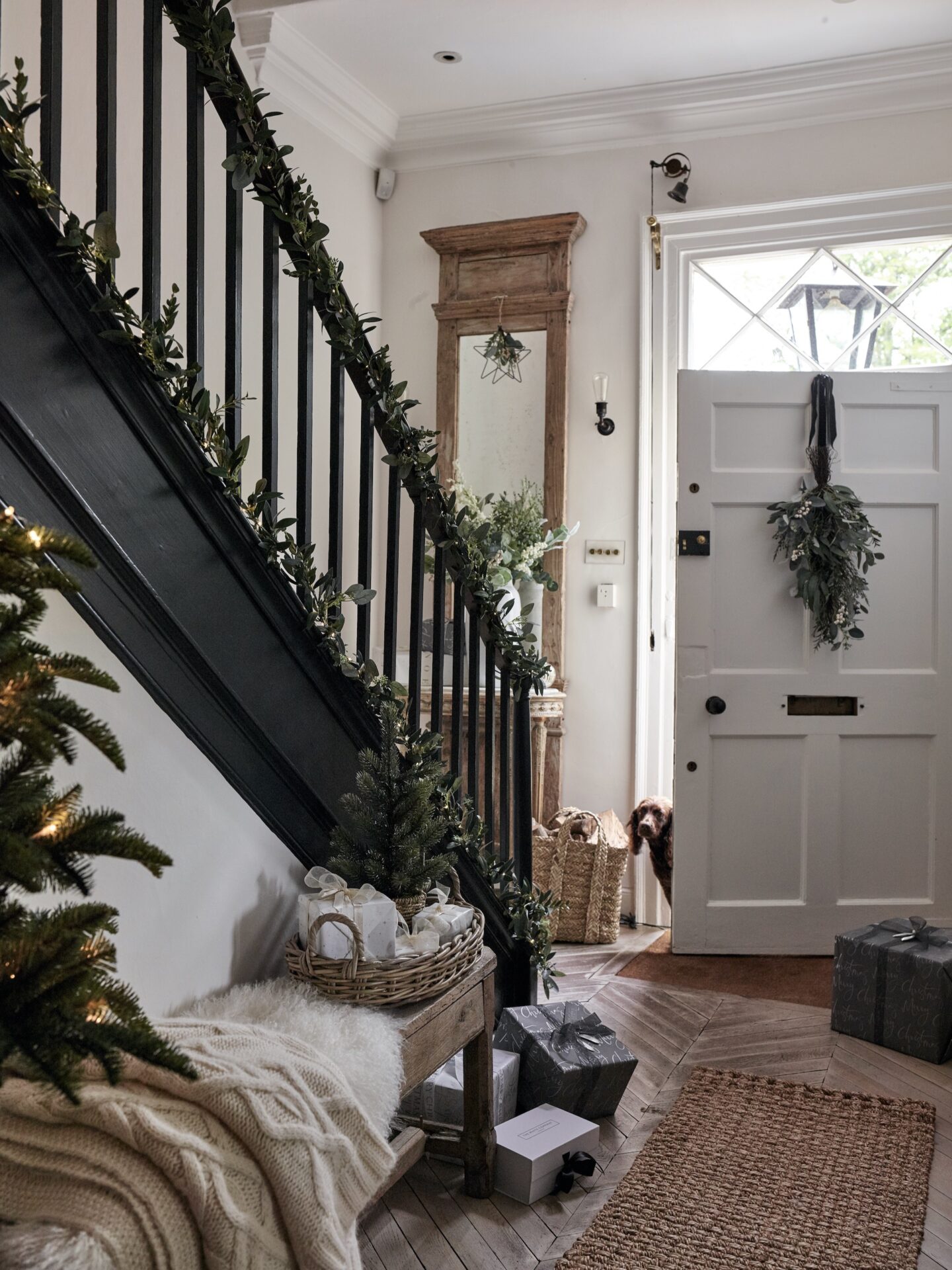 Christmas hallway with black staircase and bench covered in blankets