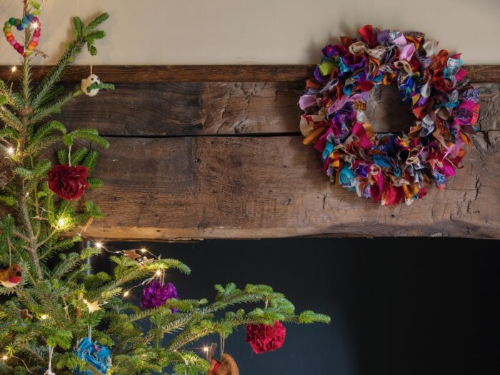 Colourful wreath made of ribbons hanging from wooden beam