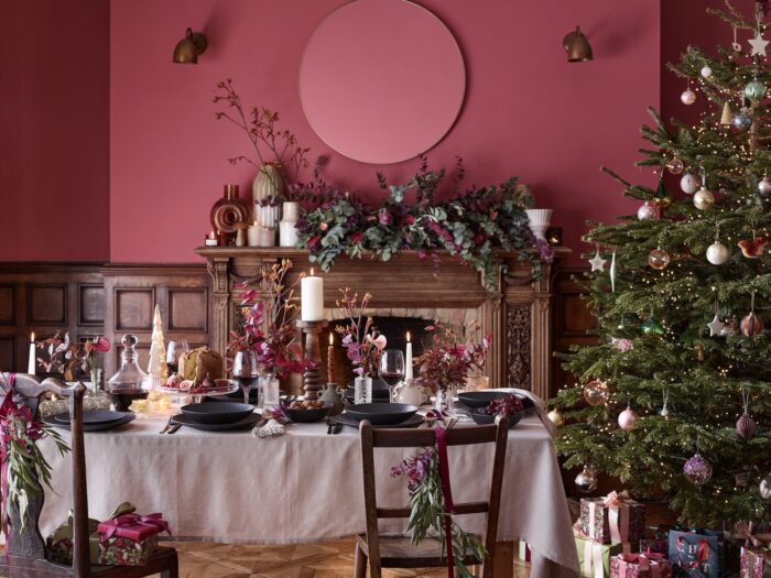 Christmas tree next to dining table with red walls and wooden fireplace