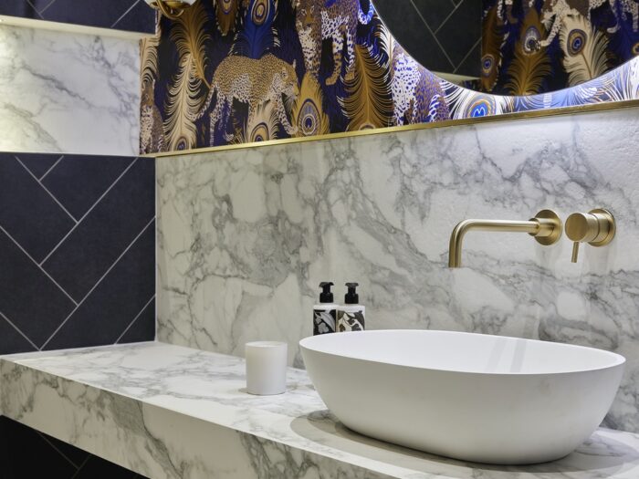 Cloakroom with marble tiled countertop and black herringbone tiled walls