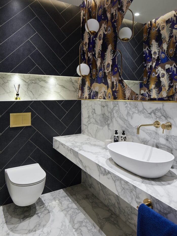 Cloakroom with marble tiled countertop and black herringbone tiled walls