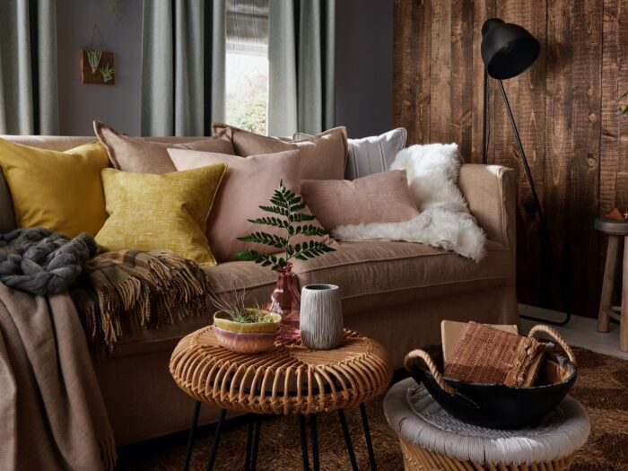 Sofa piled with cushions with wall clad in wood