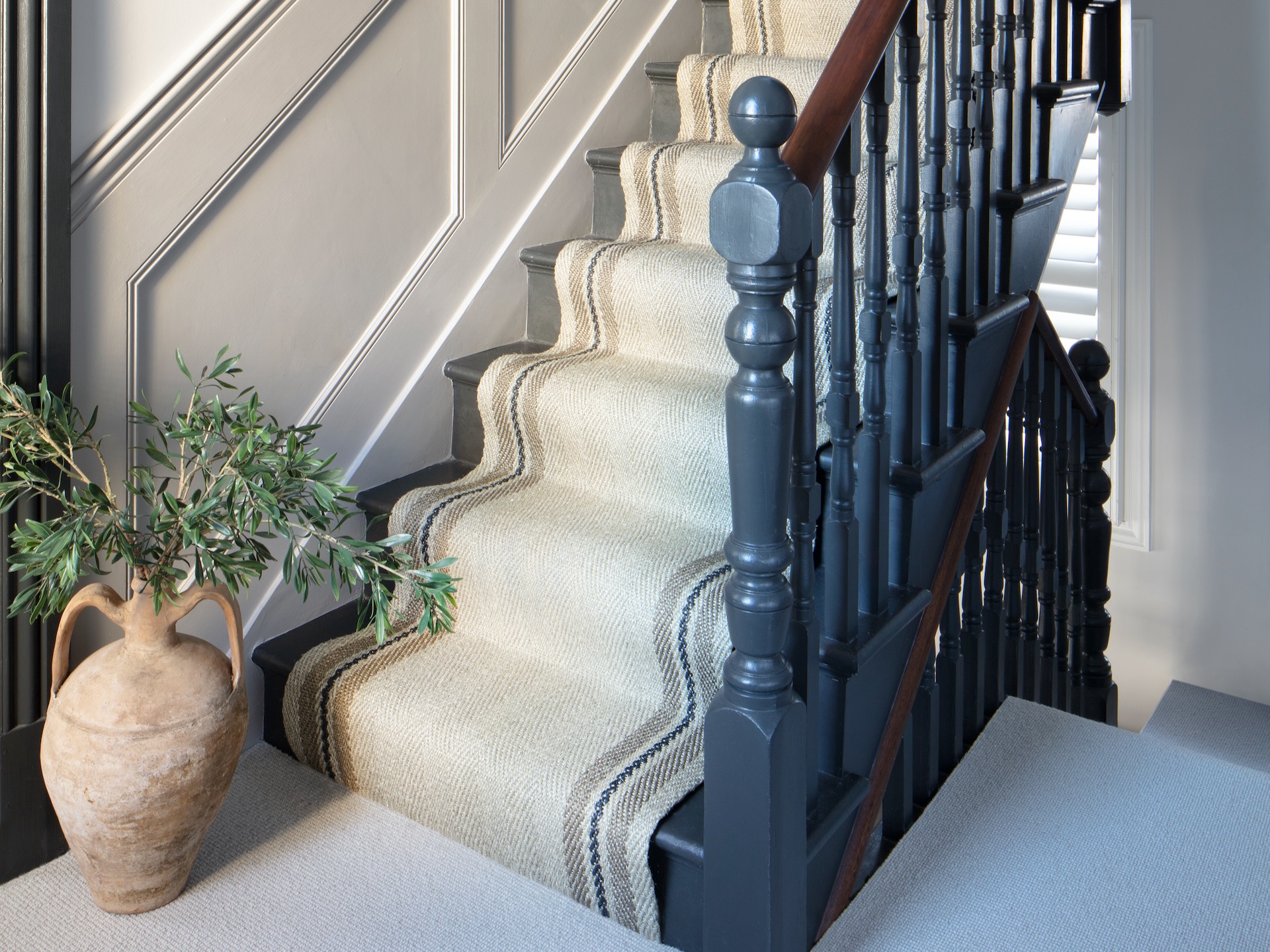 Neutral hallway with beige striped stair runner and black-painted staircase