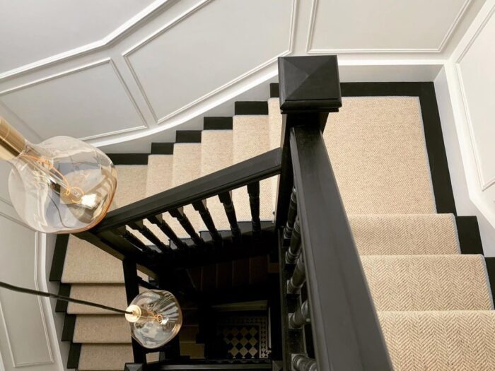 Cream herringbone carpet on winding black painted staircase