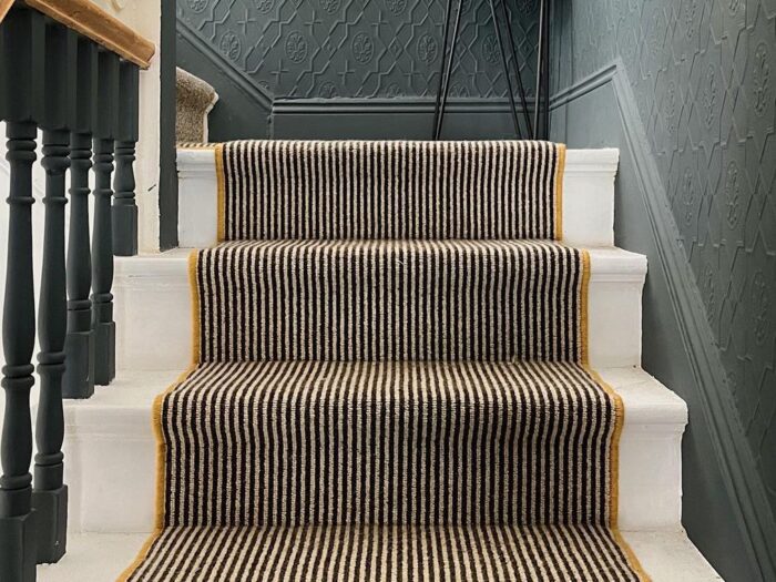 Striped stair carpet with white painted stairs and mustard edging