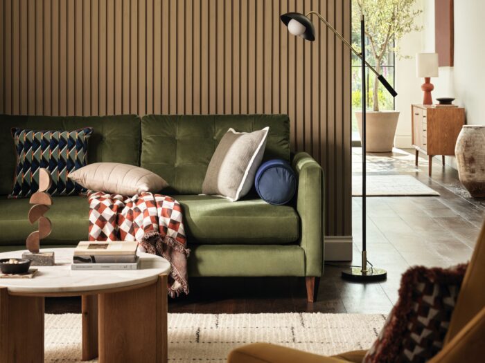 Close up of living room with contemporary slatted wall panels and green sofa