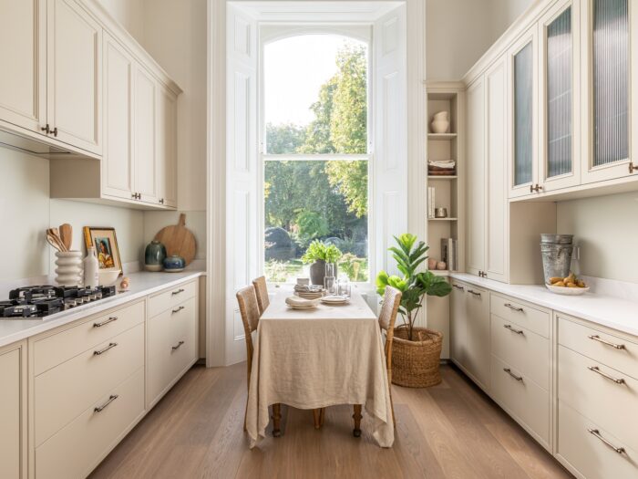 Cream coloured galley kitchen with dining table and linen tablecloth