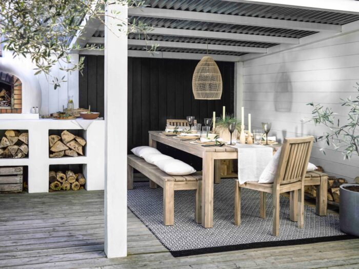Wooden garden table under gazebo next to to outdoor kitchen