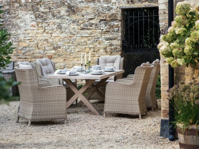 Wooden table and rattan chairs in walled garden