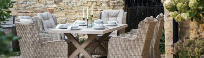 Wooden table and rattan chairs in walled garden