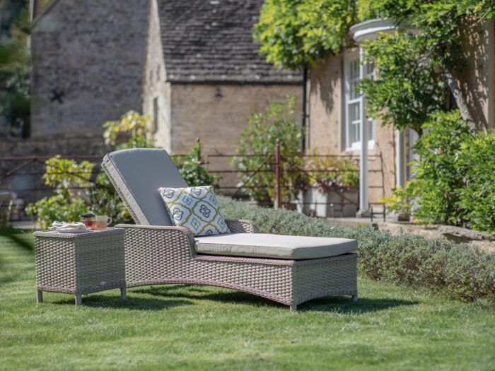 Woven sun lounger on lawn of period home