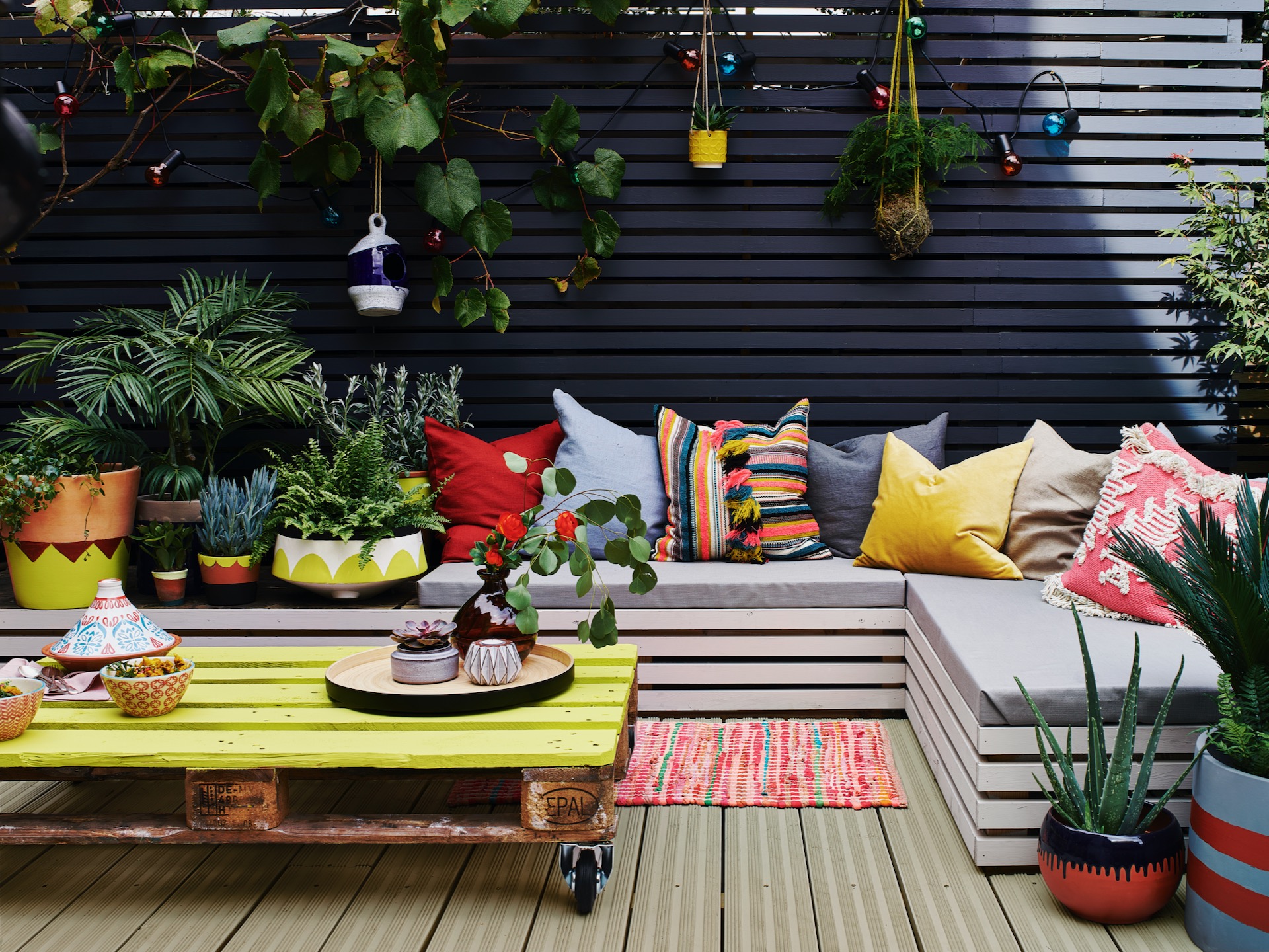 Charcoal painted garden fence with bench seating and hanging pots
