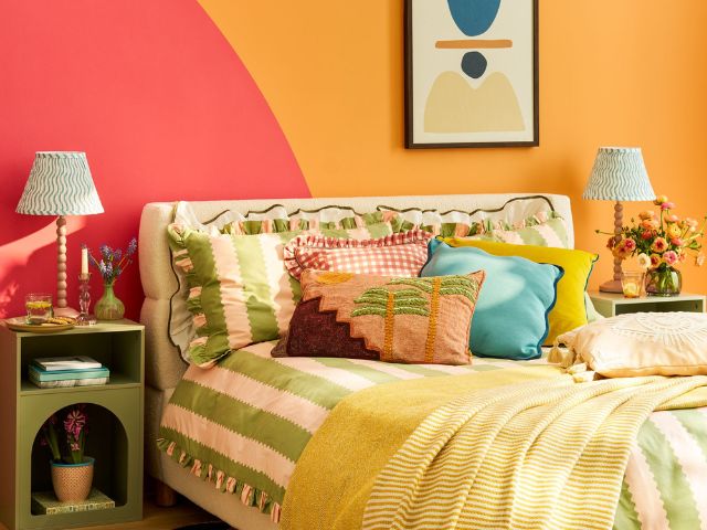 Colourful bedroom with orange and pink walls and striped duvet
