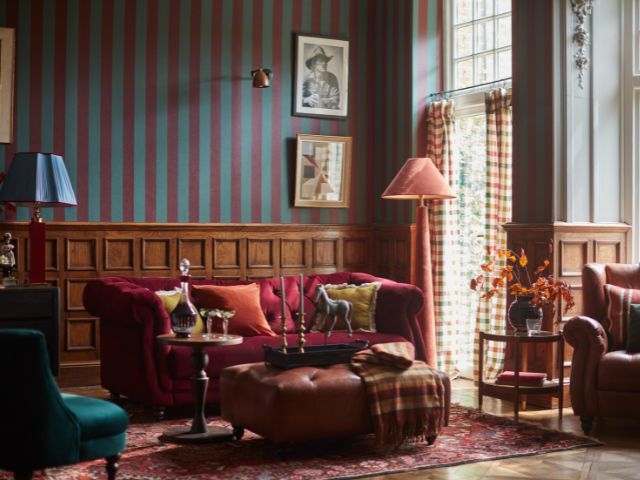 Striped wallpaper and panelled walls with a red sofa by DFS