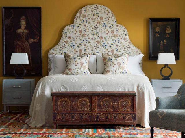 Yellow walls and a floral headboard in a bedroom by Andrew Martin